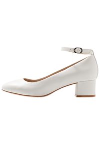 Vit läderpumps med spetsig tå, ankelrem och blockklack. Den eleganta designen har en slät yta och minimala detaljer.