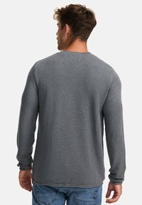 Langermet skjorte i teksturert grått stoff, med rund halslinning og avslappet passform, sammen med blå denimjeans med litt gathered mansjetter.