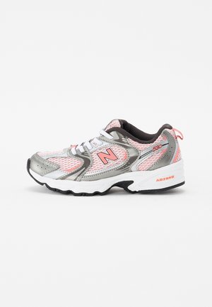 Chaussure de sport New Balance blanche, rose et grise avec détails en mesh, design à lacets et logo brandé "N" sur le côté.