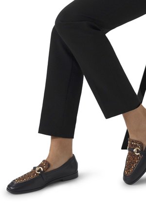 Black leather loafers with a leopard print accent, featuring gold hardware and studded details. Worn with cuffed black pants.