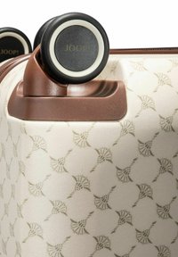 Harde koffer in roomkleur met een subtiel patroon van bladeren. Voorzien van bruine accenten en twee zwarte wielen met witte randen.