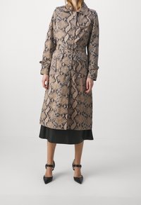 Trench-coat imprimé serpent en tons beige et marron, doté d'une taille ceinturée, d'un col cranté et de fermetures à boutons. Tissu à texture lisse.
