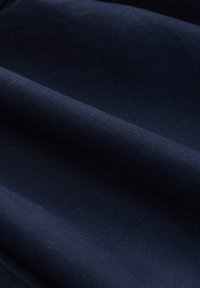 Marineblauer Stoff mit glatter Textur, der dezente Falten und ein gleichmäßiges Webmuster aufweist.