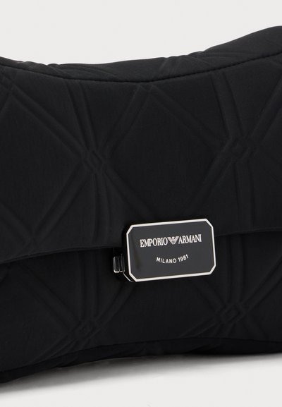 Μαύρο τσαντάκι από καπιτονέ ύφασμα με ορθογώνιο ασημί και μαύρο κούμπωμα, χαραγμένο με "EMPORIO ARMANI MILANO 1981."