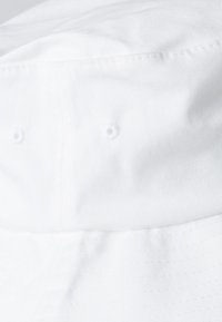White cotton bucket hat with a soft texture, featuring ventilation eyelets on the sides and a stitched brim for durability.