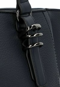 Dunkelblaue Lederhandtasche im Nahaufnahme, mit einer strukturierten Oberfläche, glatten Akzenten und drei schwarzen Metallringen für das Hardware-Detail.