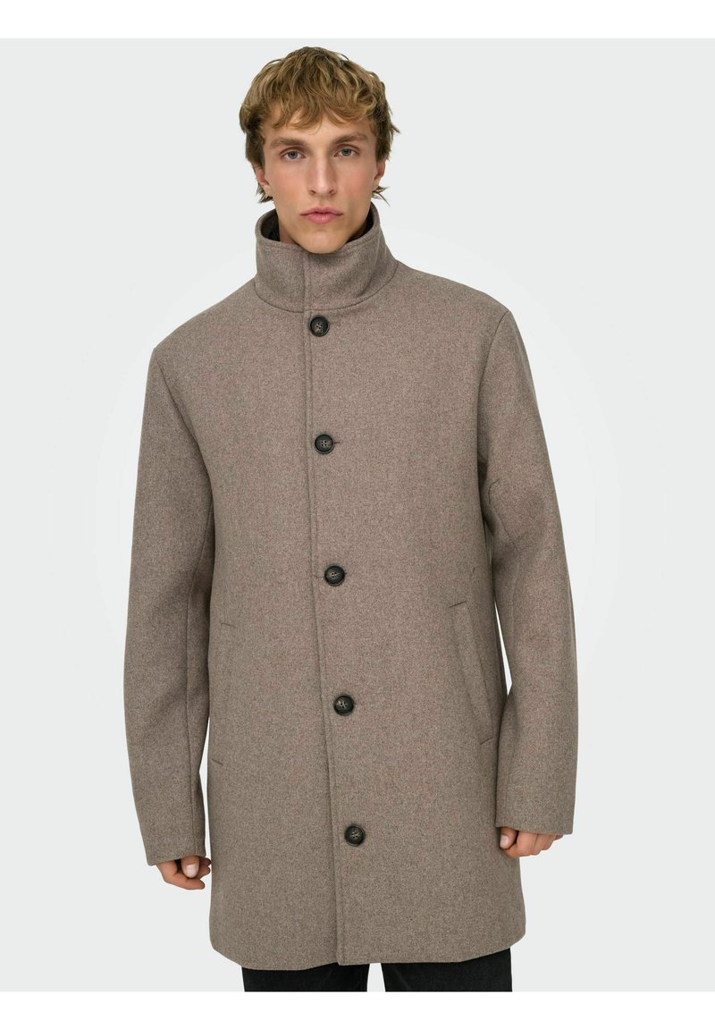 Cappotto marrone di lana con collo alto, cinque bottoni neri e tasche laterali; presenta un taglio dritto e una texture liscia.