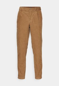 Pantalon en velours côtelé marron clair avec passants de ceinture, fermeture par boutons, plis à l'avant et jambes fuselées sur un fond uni clair.
