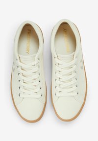 Zapatillas de lona blancas con el logo dorado de "Fred Perry", puntera redonda, diseño con cordones y suela de goma texturizada en marrón claro.