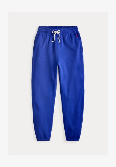 Niebieskie dresowe spodnie z polaru z elastycznym pasem, białym sznurkiem, bocznymi kieszeniami i elastycznymi mankietami, prezentowane na płasko na białym tle.