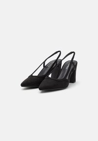Sorte semskede slingback-hæle med spids tå og en moderat blokhælfod. Har stropdetaljer og en glat inderside.