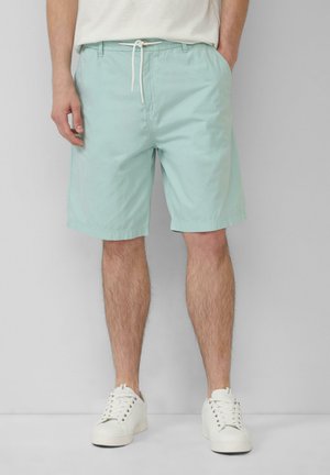 Shorts vert menthe clair en coton, dotés d'une taille avec cordon de serrage et de poches latérales, complétés par des baskets blanches.