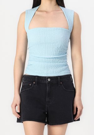 Lichtblauw gesmokt mouwloos topje met vierkante halslijn, gecombineerd met hooggetailleerde zwarte denimshorts met voorzakken en een knoopsluiting.