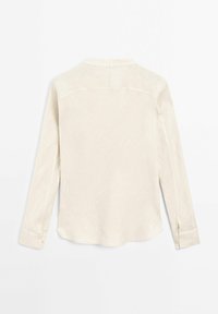 Blouse crème à manches longues avec poignets et col, vue de dos sur un fond blanc uni.