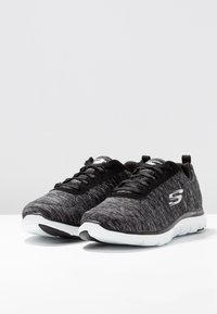 Czarno-szare buty sportowe z teksturowanym wierzchem, białą podeszwą i czarnymi sznurowadłami, z logo po boku i uchwytem na pięcie.
