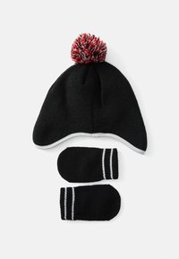 Cappello in maglia nera per l'inverno con alette per le orecchie e pompon rosso- grigio, abbinato a muffole nere coordinate con strisce bianche sui polsi.
