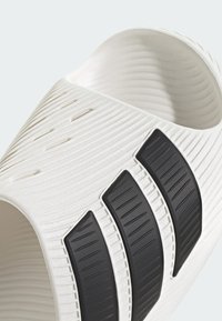 Biała teksturowana klapka na platformie z trzema czarnymi żebrowanymi paskami na pasku, odkrytymi palcami i wyściełaną podeszwą.