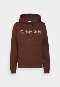 Felpa con cappuccio marrone realizzata in tessuto morbido, dotata di tasca frontale e grande logo bianco "Calvin Klein" sulla parte anteriore.