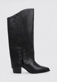 Bota de cuero negro hasta la rodilla con punta afilada, exclusivo borde plegado en la parte superior y ojales decorativos en el costado. Cuenta con un tacón apilado.