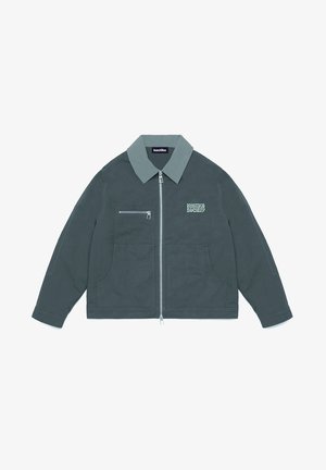 Mørkegrå glidelåsjakke med lys grå krage, brystlomme med glidelås, to nedre lommer, og "Kootiko Society"-logo på venstre bryst.