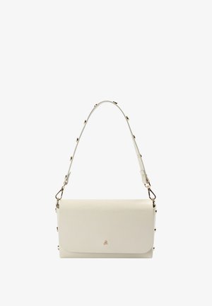 Bolso de mano rectangular de cuero color crema con una correa para el hombro tachonada y un pequeño emblema de calavera dorada en la solapa frontal.