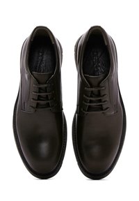 Chaussures en cuir marron foncé avec une finition lisse, bout rond, design à lacets et semelle intérieure texturée. Style minimaliste sans marque visible.