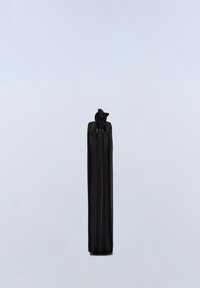 Zwarte ritstas met een verticale vorm en een gestructureerd oppervlak. Voorzien van een gedetailleerde ritselfpositie in de vorm van een dier aan de bovenkant.