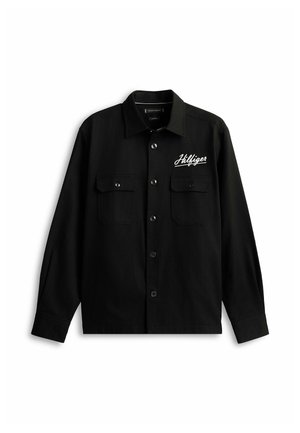 Chemise noire à manches longues avec boutons sur le devant, deux poches poitrine et logo script "Hilfiger" blanc sur la poitrine gauche.