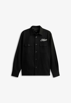 Chemise noire à manches longues avec boutons sur le devant, deux poches poitrine et logo script "Hilfiger" blanc sur la poitrine gauche.