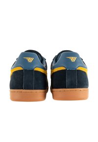 Marineblaue Wildledersneaker mit blauen Lederakzenten und gelben Seitenstreifen. Helle Gummisohle mit subtiler Textur und geprägtem Branding an der Ferse.