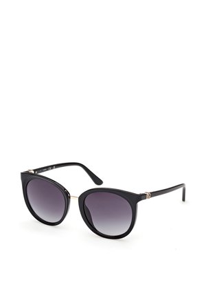 Lunettes de soleil noires œil de chat avec verres dégradés foncés et pont doré fin, présentées sur fond blanc.