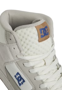 Vysoké tenisky v bílé a světle šedé barvě, s vrchní částí z prodyšné síťoviny a semiše, bílými tkaničkami a hnědým koženým logem s modrým písmem.