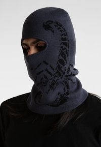 Balaclava de punto en azul oscuro con un gráfico de escorpión negro. Ofrece cobertura completa de la cabeza y agujeros para los ojos y la boca. Textura suave.