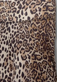 Materiał w leopardzie cętki z kolorystyką w odcieniach brązu i beżu, miękką teksturą i gładkim wykończeniem, szerokim pasem i detalami w postaci przeszyć.