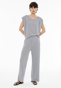 Graues Zweiteiler-Outfit mit einem locker sitzenden Oberteil mit kurzen Ärmeln und weiten Hosen. Weicher, strukturierter Stoff und entspannte Silhouette.