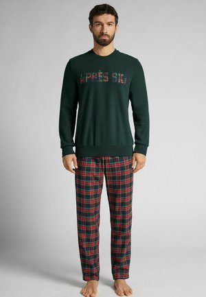 Groene fleece sweatshirt met "APRES SKI" in geruite letters, gecombineerd met rood-en-marineblauw geruite pyjamabroek. Zachte textuur, relaxte pasvorm.