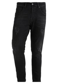 Černé potrhané džíny se slim fit, které mají jemně vybledlé oblasti, trhliny a kovové detaily v oblasti pasu. Klasický design se pěti kapsami.