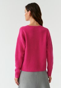 Magenta Strickpullover mit lockerer Passform, geripptem Saum und Bündchen sowie rundem Ausschnitt; weicher Stoff mit leicht abgesenkten Schulternähten.
