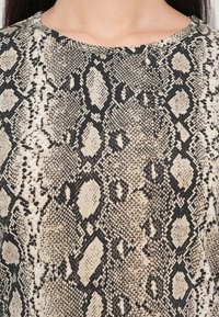 Beige and black snake-print fabric with a textured pattern, featuring a round neckline and a smooth surface.