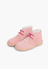 Un par de botas de tobillo de ante rosas con suelas beige y cordones rosas, exhibidas sobre un fondo blanco.