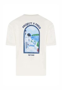 Camiseta de color crema con un gráfico en azul y blanco de Santorini, con el texto "PROJECT X PARIS" y "SANTORINI" en azul marino.