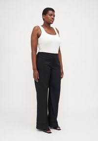 Black wide-leg trousers with a button closure, paired with a white fitted tank top. Smooth fabric with clean lines and a minimalist design.