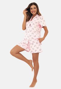 Krótki zestaw piżamowy z krótkim rękawem w jasnoróżowym kolorze w pasy, z kwiatowymi akcentami. Materiał wydaje się miękki i lekki, odpowiedni na odzież nocną.