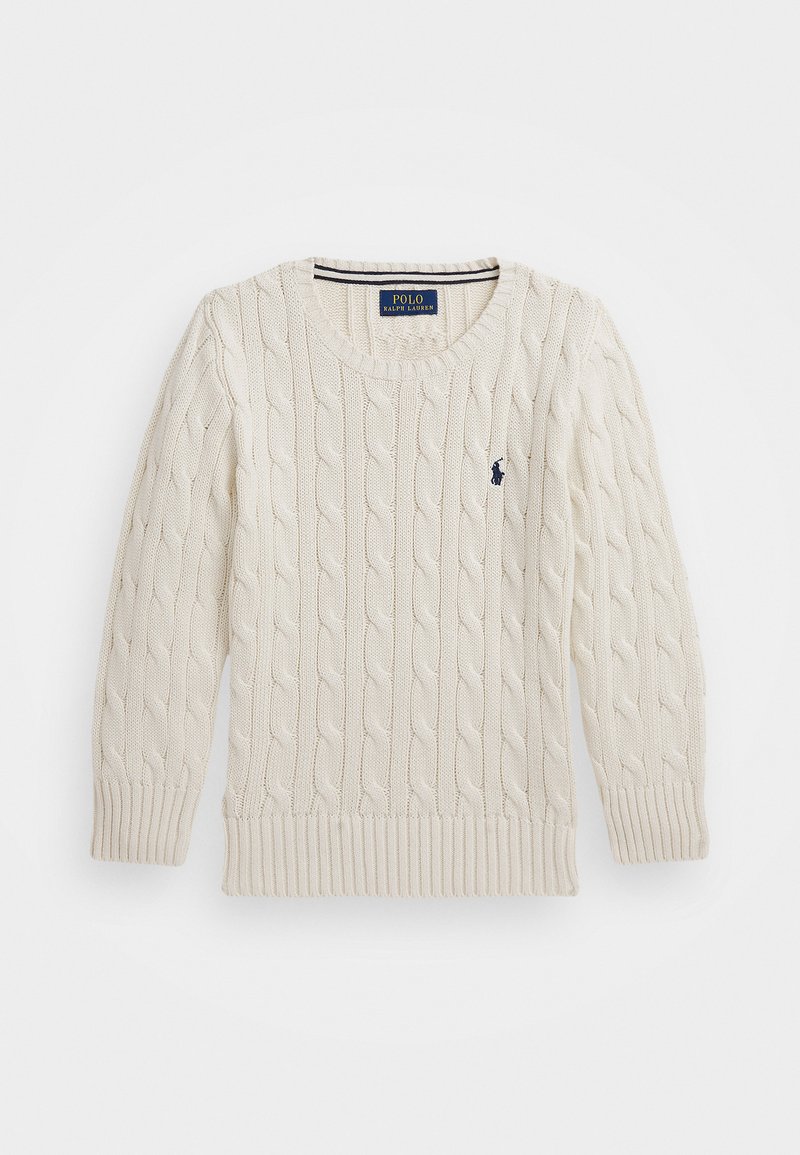 Kreminės spalvos megztinis su kabelių raštu, su išrišimu apatinėje dalyje ir ant rankovių. Ant krūtinės yra tamsiai mėlynas logotipas ir apvalus iškirpimas.