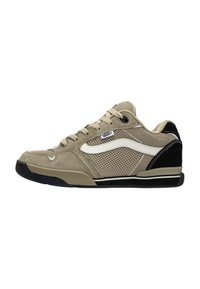 Zapatilla beige con materiales de malla y ante, que presenta una franja lateral blanca, un acento en el talón negro y una suela de goma texturizada.