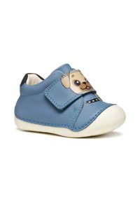 Scarpa in pelle blu con strap in velcro, caratterizzata da un design con faccia di cane. Suola in gomma bianca e cuciture blu a contrasto lungo i bordi.