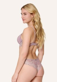 Souprava krajkového spodního prádla v jemné levandulové barvě s propracovanými květinovými vzory. Obsahuje nastavitelné ramínka a jemné detaily na okrajích.