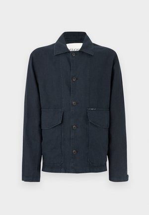 Veste bleu marine foncé en tissu texturé avec une coupe droite, dotée d'un col, de boutons sur le devant et de deux poches poitrine.