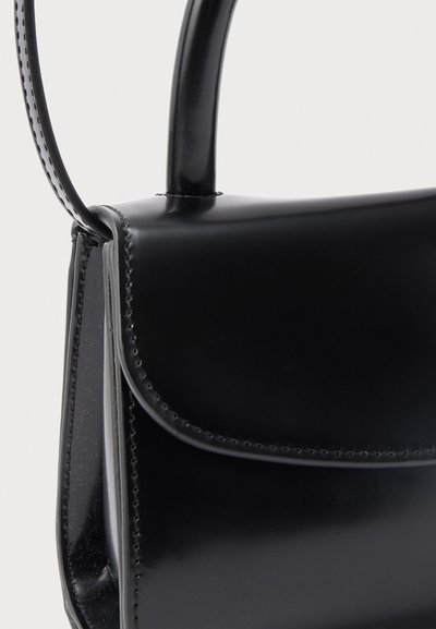 Čierna hladká kožená kabelka s klopovým zapínaním a zaoblenou rukoväťou pripevnenou na vrchu.