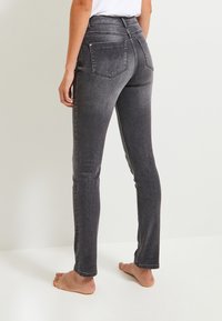 Höga midjebyxor i slim fit i mörkgrå denim. Har bakfickor och en slät textur med lätt urtvättning längs benen.